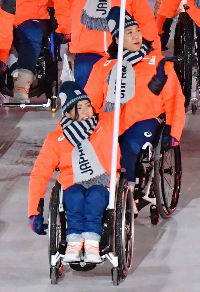 　平昌冬季パラリンピックの開会式で、日本選手団の旗手を務め手を振りながら入場行進する村岡桃佳選手（手前）