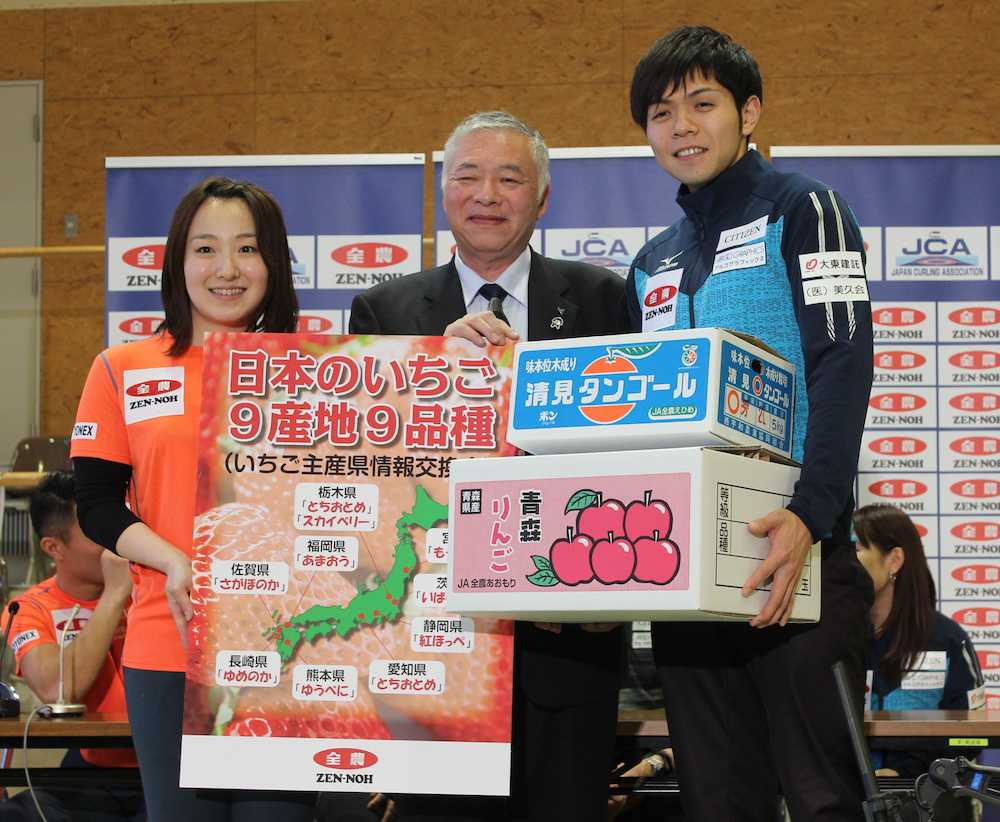 全農日本混合ダブルスカーリング選手権の記者会見で全農広報部の落合成年部長（中央）から果物を贈呈され、選手を代表して受け取った藤沢と両角