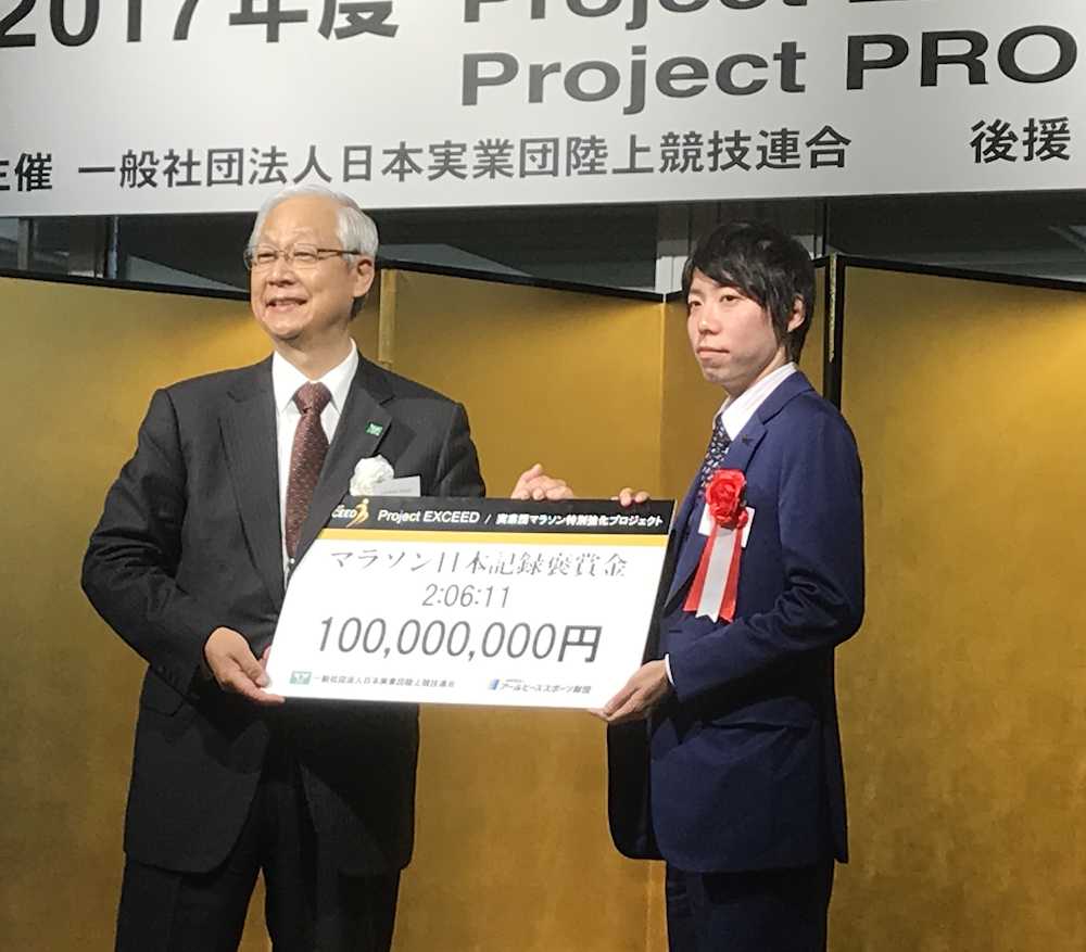 日本新記録の報奨金１億円のボードを手に写真に収まる設楽悠太（右）と日本実業団連合の西川会長
