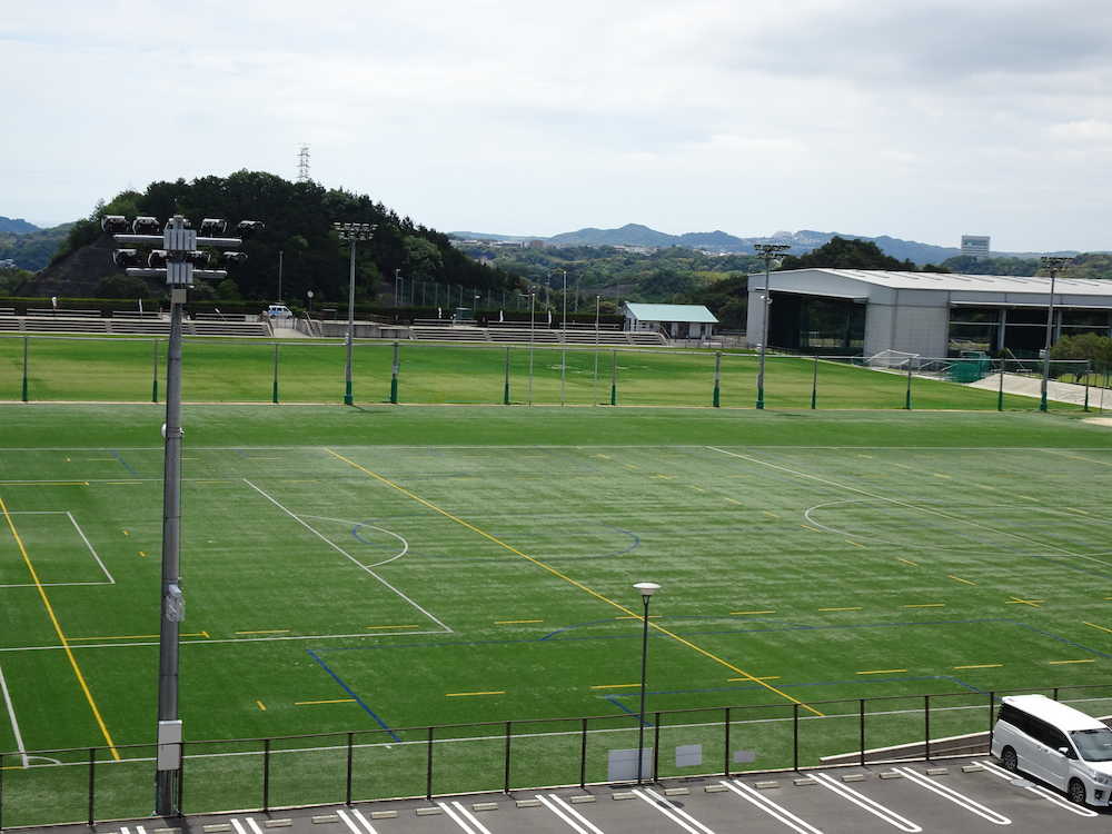 人工芝（手前）、天然芝（奥）、屋内練習場（右奥）のグラウンドを備えた上富田町スポーツセンター。他にもう１面、天然芝のグラウンドがある