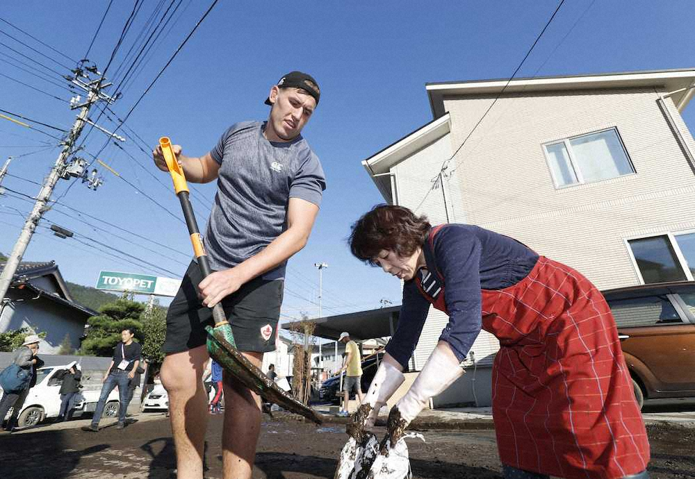 住民の女性（右）とともに道路の泥を取り除くラグビーW杯カナダ代表のジョシュ・ラーセン