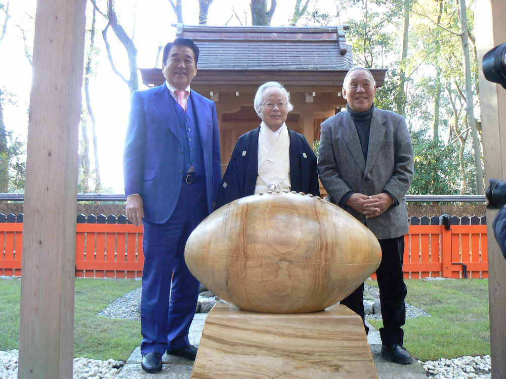 ラグビーボール形のさい銭箱を前に笑顔を見せる左から原代表、新木宮司、坂田会長