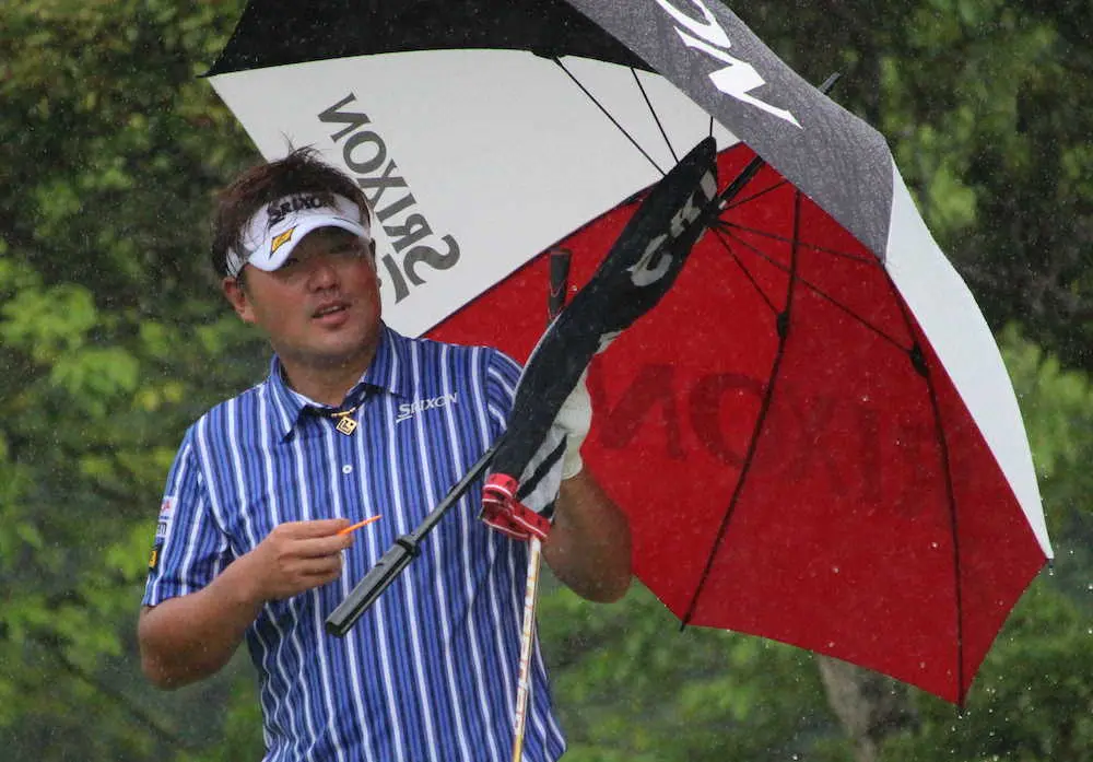 <九州オープン・第2日>雨の中、傘を差してショットの順番を待つ秋吉、このあと競技はサスペンデッドに