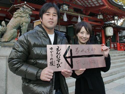 生田神社の縁結びの銅版に名前を書きポーズをとる葛城と中山知紗