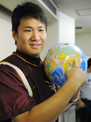 北京五輪野球の日本代表に選ばれ、地球儀上の北京付近を指さす田中