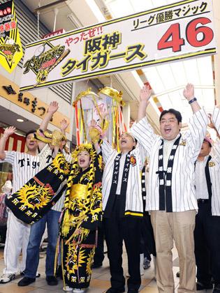 阪神の優勝マジック「４６」をボードに表示し、万歳して喜ぶ商店街のファン