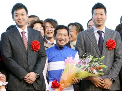 有馬記念のプレゼンテーターを務めたサブロー(左）と大松（右）は優勝ジョッキーの安藤勝己騎手が笑顔で記念撮影する