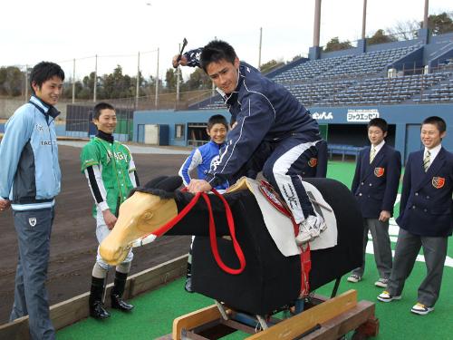 日本ハム・中村（左端）、競馬学校の生徒らが見守る中、木馬に乗ってトレーニングする運天ジョン・クレイトン