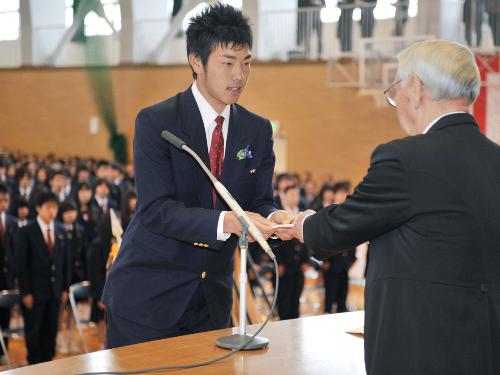 花巻東高の卒業式で、小田島順造校長に記念品の目録を手渡す西武の雄星