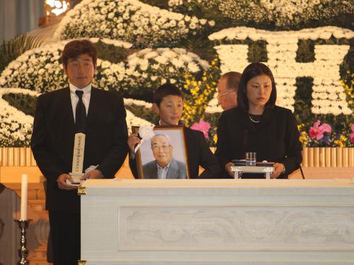 故・田宮謙次郎氏の棺の前で涙をこらえる（左から）施主であり長男の孝志さん、孫の悠裕くん、孝志さんの妻・文代さん