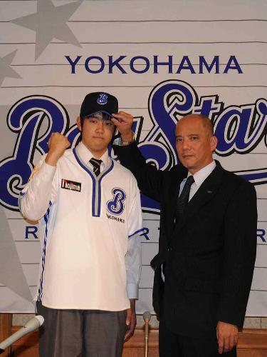横浜との仮契約を終え、河本取締役（右）に帽子をかぶせてもらう法大・加賀美
