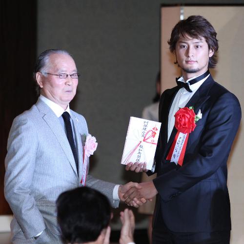 巨人・長嶋茂雄終身名誉監督（左）から特別賞を手渡され、握手を交わす日本ハム・ダルビッシュ