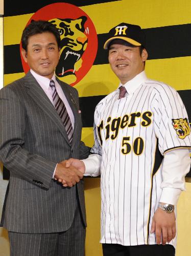 入団記者会見で阪神・真弓監督（左）と笑顔で握手する藤井彰人捕手