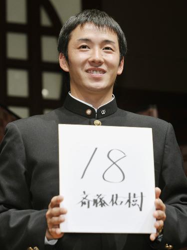 日本ハムと仮契約を交わし、背番号を書いた色紙を手に笑顔を見せる斎藤佑樹投手