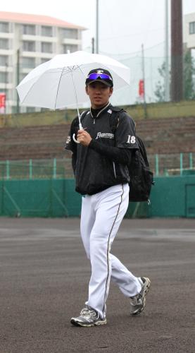 雨の中、傘を差して球場に入る斎藤