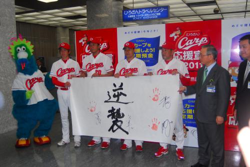 野村監督（右から３番目）直筆の「逆襲」にサインと手形を入れ、決意を示した前田智（左から３番目）らカープ選手