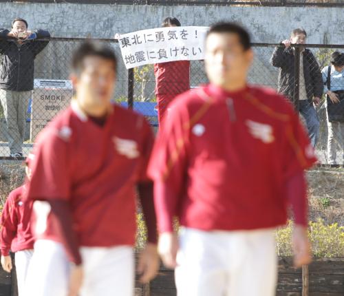 「東北に勇気を！！地震に負けない！」と書かれた横断幕を背に練習する楽天の選手たち