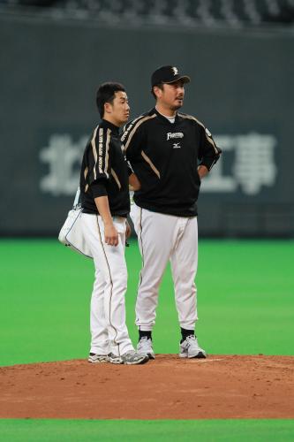 マウンドで日本ハム・吉井コーチ（右）と話す斎藤