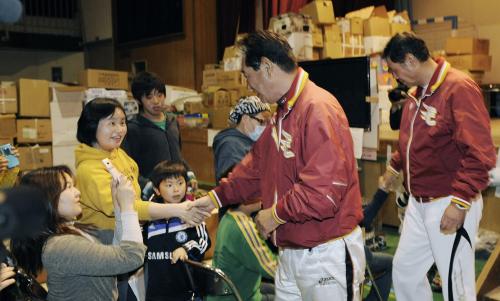 避難所を訪れ、子どもたちと握手し激励する楽天の星野監督。右端は田淵ヘッドコーチ