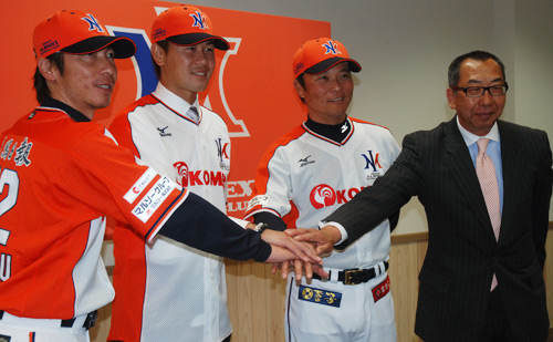 ユニフォームに袖を通し、藤橋社長（右）、橋上監督（右から２番目）、高津投手（左）と合わせる正田（左から２番目）