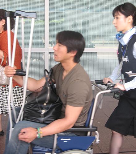 広島から羽田空港に到着し、車椅子に乗って迎えの車に向かう巨人・小笠原