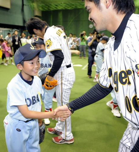 阪神タイガースの選手と笑顔で握手を交わす少年