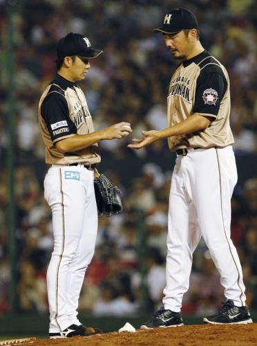 ５回、１死満塁の場面で降板を告げられ、吉井コーチ（右）にボールを渡す日本ハム先発の斎藤