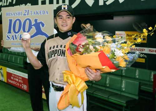 通算１００セーブを達成し、花束を手に笑顔を見せる日本ハムの武田久