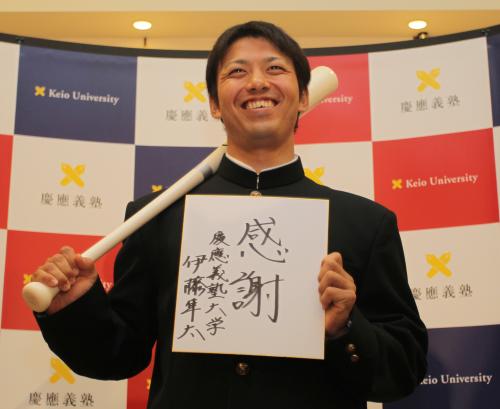 阪神から１位指名を受け、「感謝」と書いた色紙とバットを手に笑顔の慶大・伊藤