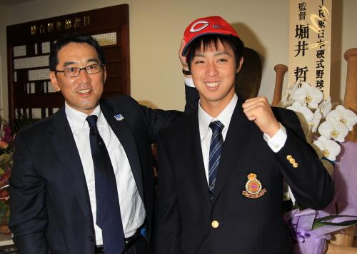 指名あいさつに合宿所を訪れた広島・野村監督（左）に帽子をかぶらせてもらって笑顔の明大・野村