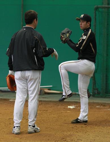 ブルペンで吉井コーチ（左）とフォームをチェックする日本ハム・斎藤