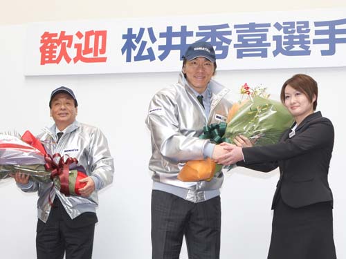 コマツの茨城工場を訪問し女性社員から花束を贈られる松井と父・昌雄さん（左）