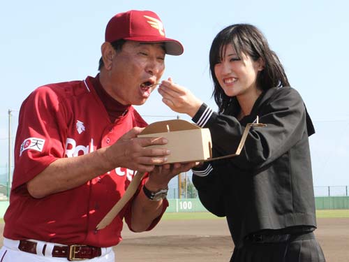久米島高３年の神里優香さんにチョコレートケーキを食べさせてもらう楽天・星野監督