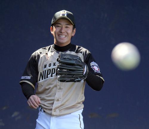 日本ハムの斎藤は、ブルペンで投球練習中に笑顔を見せる