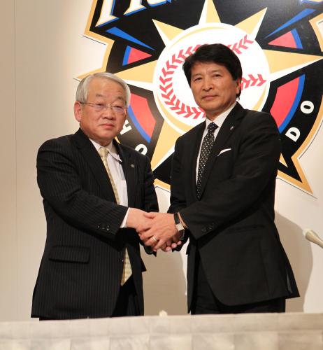 会見で握手する日本ハムの小林新オーナー（左）と大社オーナー代行