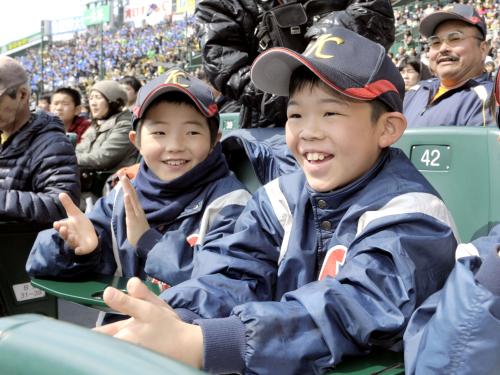 宮城県石巻市から選抜高校野球大会に招待され、笑顔で観戦する永井倹之介君（右）らスポーツ少年団の小学生