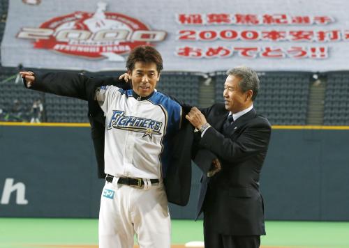 名球会の山田久志氏（右）からブレザーを着せてもらう日本ハム・稲葉