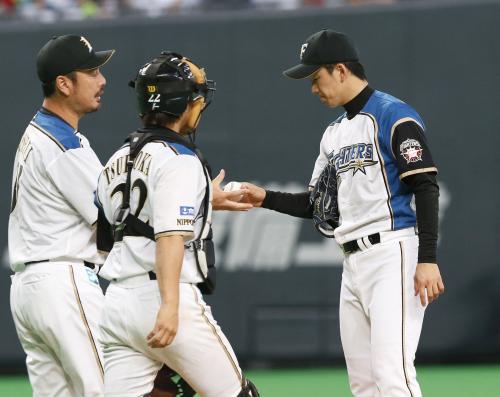 ６回途中、吉井投手コーチ（左）にボールを渡し、降板する日本ハム・斎藤（右）。捕手鶴岡