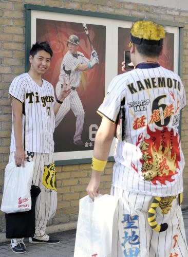 ヤクルト戦を前に、甲子園球場の金本知憲外野手の写真の前で記念撮影する阪神ファン