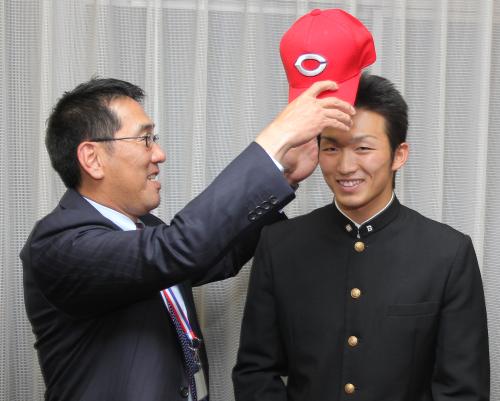 ２位指名した二松学舎大付・鈴木（右）に帽子をかぶせる広島・野村監督