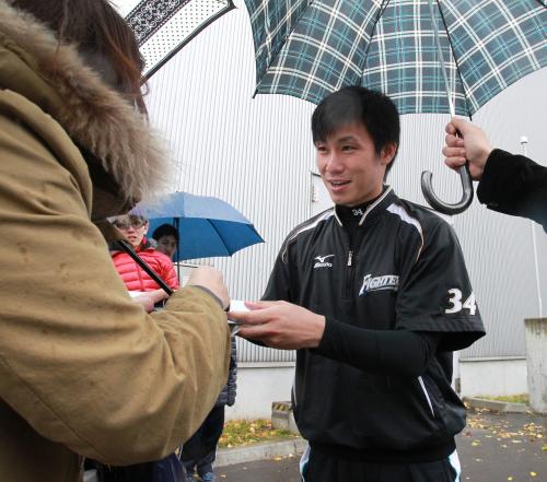 雨の中、ファンにサインする日本ハム・吉川