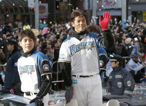 パ・リーグ優勝パレードで、沿道のファンの声援に応える日本ハム・稲葉（右）と武田勝