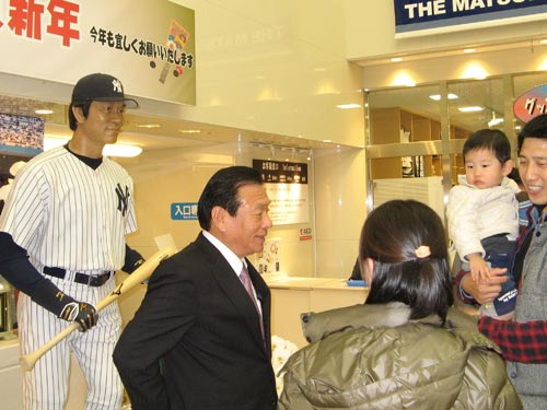 松井氏の人形の前で、来場者のファンにあいさつをする父・昌雄さん（中央）