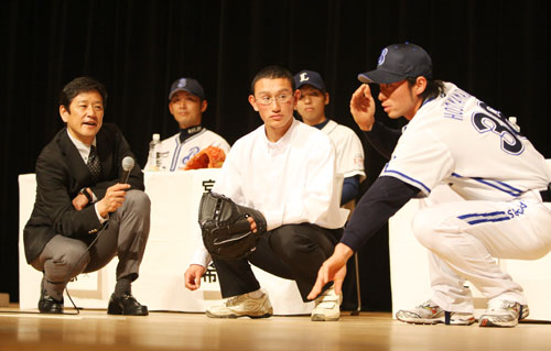 ０９年１２月、高校生にキャッチングの指導をする横浜・細山田（右）とコーディネーターを務める栗山現日本ハム監督（左）