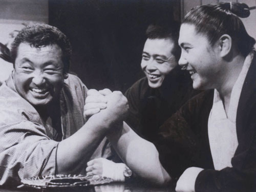 １９６２年、腕相撲をする力道山（左）と大鵬（右）を笑顔で見守る王