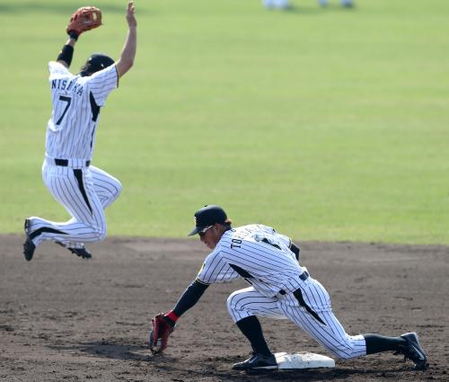 西岡（左）がジャンプして避ける送球を好捕する阪神・鳥谷
