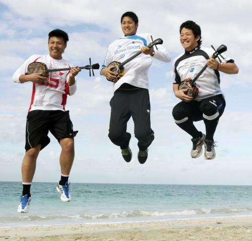沖縄伝統楽器の三線を抱えて、ジャンプする日本ハムの（左から）森本、大谷、宇佐美