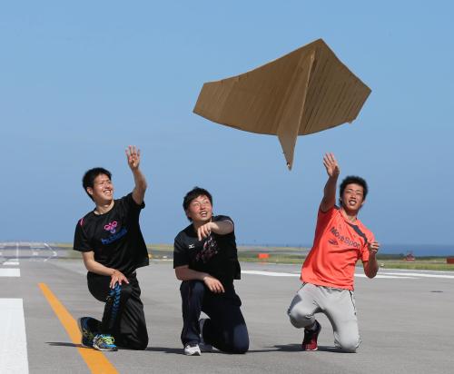 ３月に開港する新石垣島空港の滑走路で、特大の紙飛行機を飛ばすロッテの（左から）川満、松永、加藤