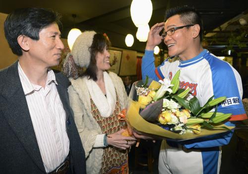 営んできた台湾料理店の営業が最終日となり、常連客から花束を贈られる中日ＯＢの郭源治さん（右）
