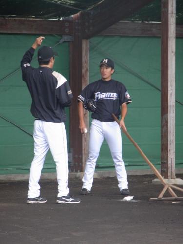 秋季キャンプ最終日にブルペン入りした日本ハム・斎藤（右）は、投球練習後に厚沢投手コーチと会話を交わす